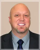 Headshot of a smiling man in a suit.