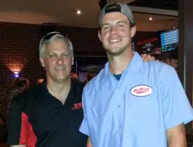 Two men smiling at a restaurant.