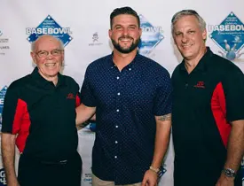 Three men smiling at a baseball event.