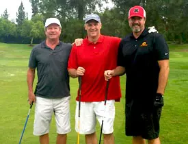 Three men smiling on a golf course.