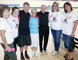 Group of people smiling at a bowling alley.