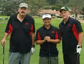 Three men in golf attire on a course.